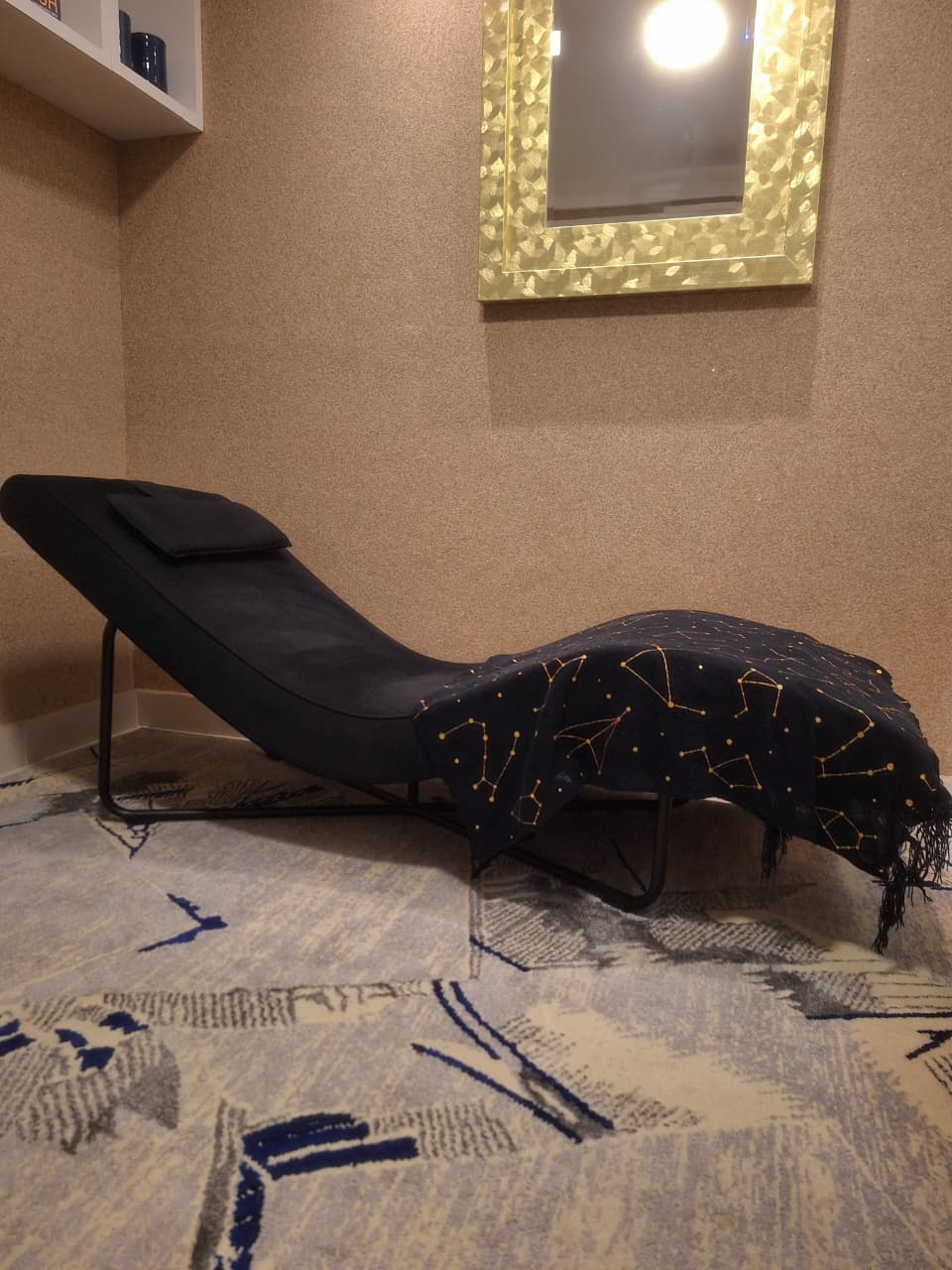 Divã preto com manta estampada de constelações douradas