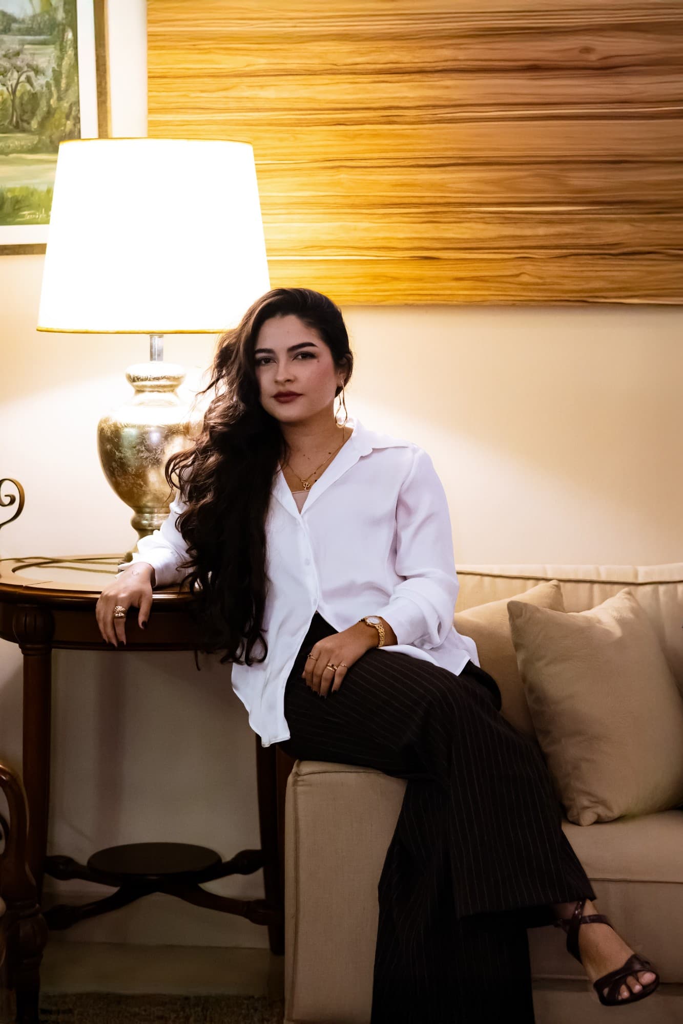 Nicolle Vilante sentada no consultório, com luminária e sofá ao fundo